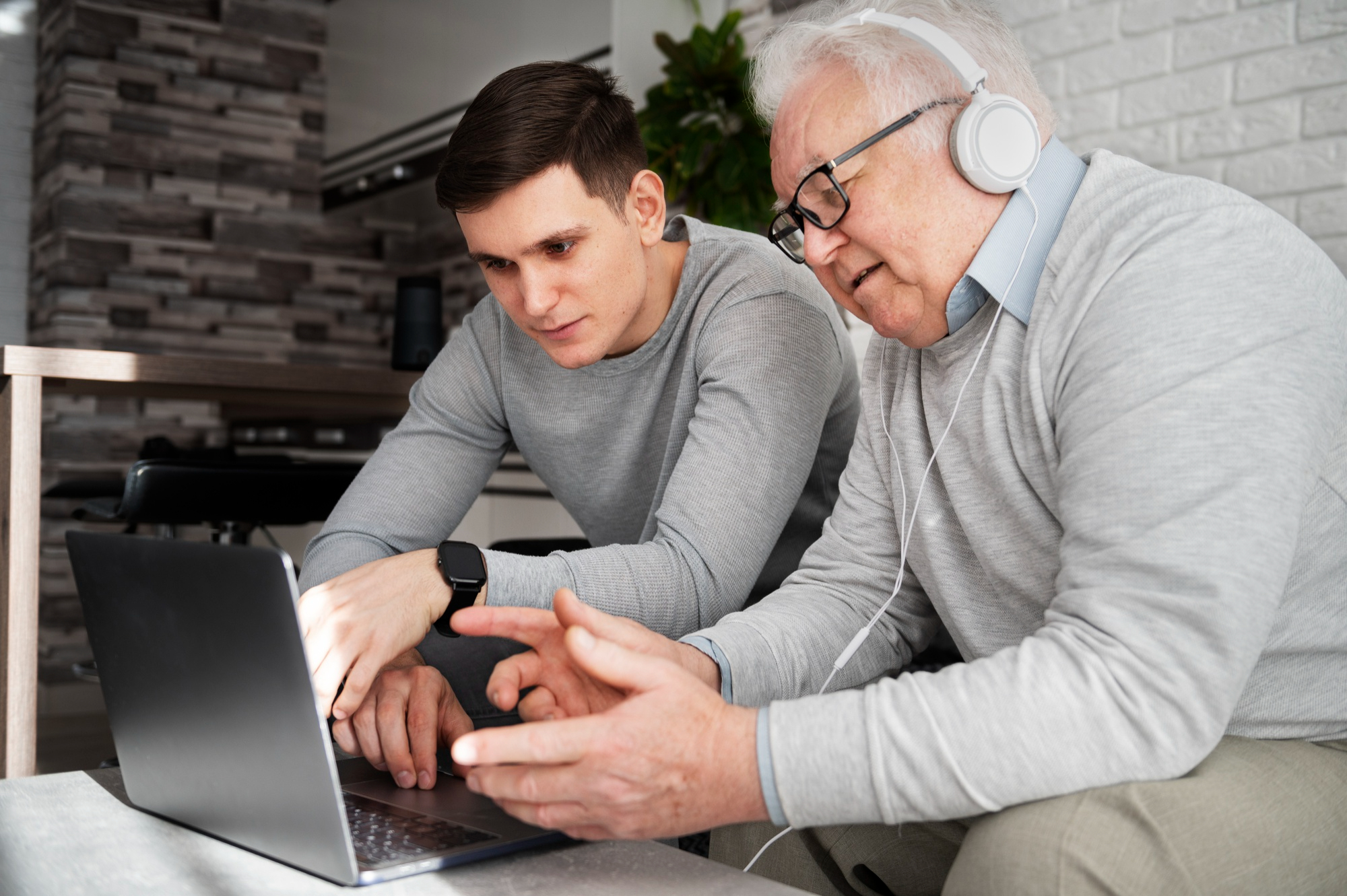 Technology instructor assisting a senior man with a laptop